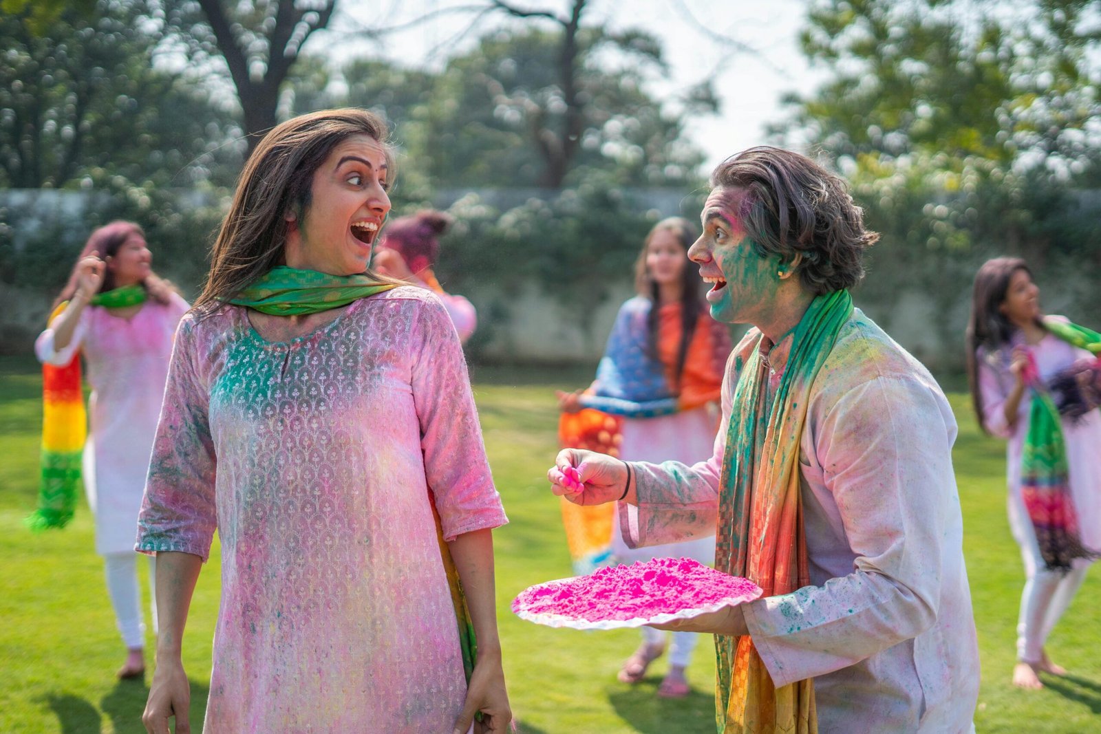 A vibrant and joyful Holi celebration with people covered in colorful powders, outdoors.
